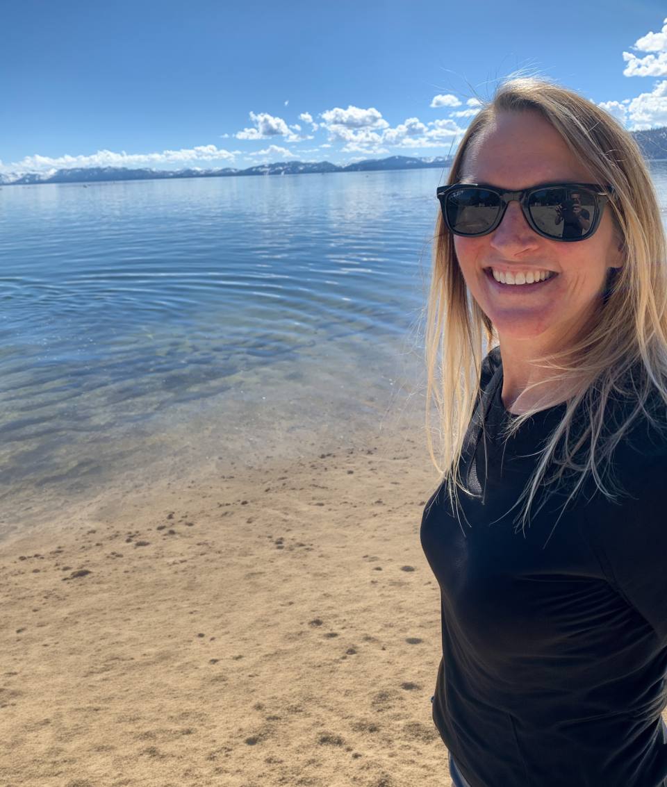 Laura Goethe smiling on the shore of a mountain lake.