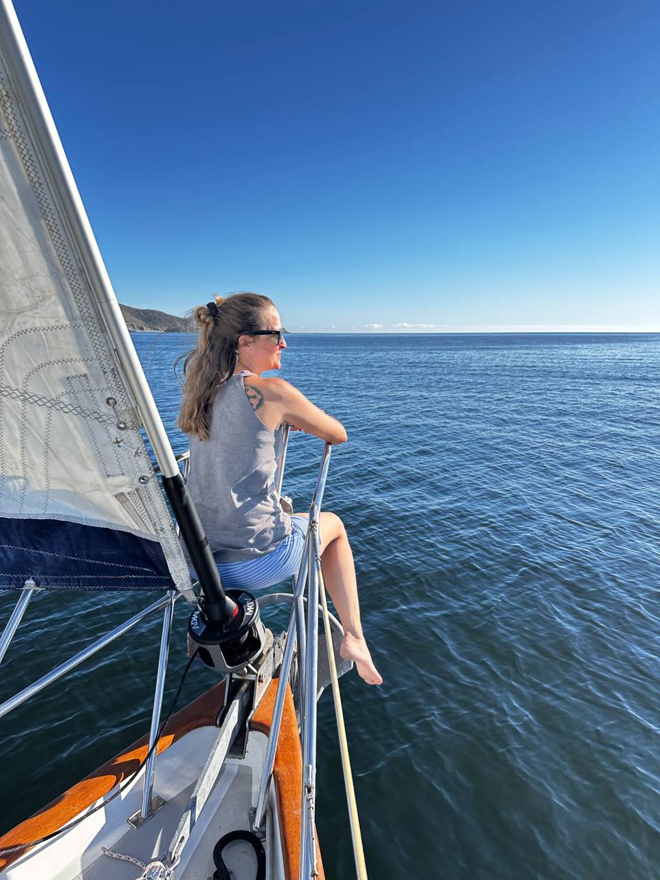 Laura sitting at the bow of a sailboat, looking out over open water.